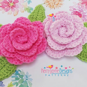May include: Two crocheted flowers with green leaves. The flowers are pink and light pink. The flowers are on a white background with watercolor flowers.