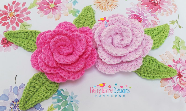 May include: Two crocheted flowers with green leaves. The flowers are pink and light pink. The flowers are on a white background with watercolor flowers.