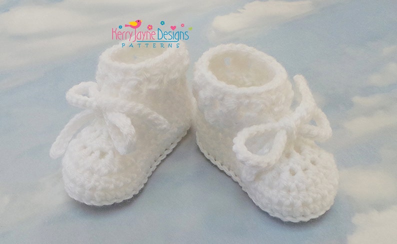 Puede incluir: Botitas de beb&eacute; de ganchillo blancas con un lazo en cada zapato. Las botitas tienen un delicado borde de encaje.