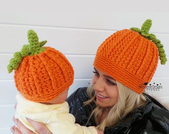 May include: Two orange crochet pumpkin hats with green stems and curly vines. The hats feature a ribbed texture. The text Kerry Jayne Designs Patterns and Crochet Pattern - 6 Sizes is visible on the image. The hats are worn by two individuals.
