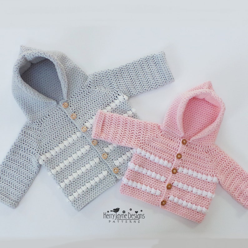 May include: Two crocheted hooded jackets with button closures. The jacket on the left is gray with white stripes and the jacket on the right is pink with white stripes. Both jackets have a small white pom-pom on each stripe.  "Kerry Jayne Designs Patterns" is printed on the bottom of the image.