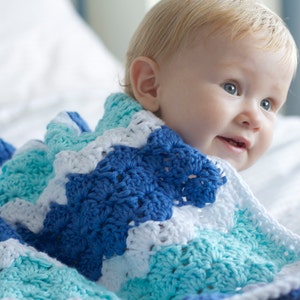 Pode incluir: Uma manta de crochê feita à mão em tons de azul, branco e turquesa. A manta tem um padrão texturizado em forma de chevron. A manta macia e aconchegante é perfeita para um bebê ou criança.