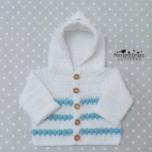 May include: White crocheted hooded cardigan with blue and white stripes and wooden buttons. The cardigan has a hood and long sleeves.