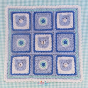 K&ouml;nnte beinhalten: Eine blaue und wei&szlig;e geh&auml;kelte Babydecke mit einem sich wiederholenden Muster aus B&auml;ren und Kreisen. Die Decke hat einen wei&szlig;en geh&auml;kelten Rand mit einem hellblauen und gr&uuml;nen Besatz.