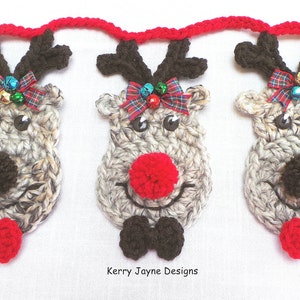 Puede incluir: Una guirnalda de tres cabezas de reno de crochet con lazos rojos y negros, cuernos marrones y narices de pomp&oacute;n. Los renos est&aacute;n unidos con una cuerda roja de crochet. El texto "Kerry Jayne Designs" es visible en la parte inferior de la imagen.