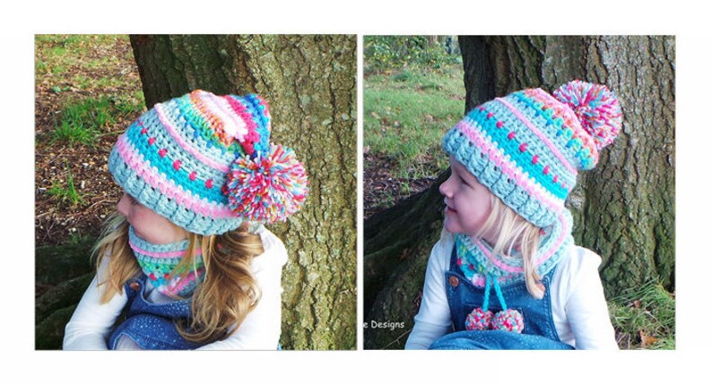 May include: Two children wearing matching crocheted hats and neck warmers. The hats are blue, pink, and white with colorful pom-poms. The neck warmers are blue, pink, and white with small pom-poms.