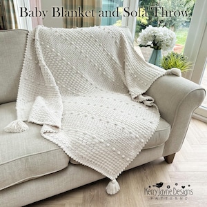 Puede incluir: Manta para bebé y sofá de color crema con un diseño de ganchillo texturizado. La manta presenta un patrón de puntos en relieve y líneas diagonales, sobre un sofá gris claro. Borlas adornan las esquinas. El texto "Baby Blanket and Sofa Throw" está en la parte superior.