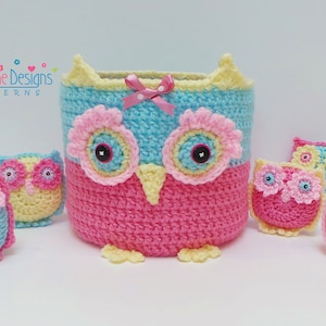 Peut inclure: Un ensemble de jouets hiboux en crochet, comprenant un grand panier en forme de hibou aux couleurs rose et bleu. Le panier a un nœud jaune et des yeux noirs. Il y a quatre petits hiboux en rose, jaune et bleu.