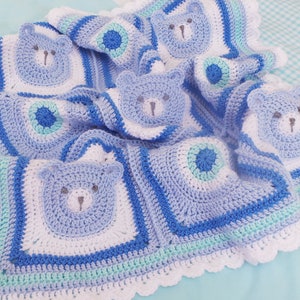 K&ouml;nnte beinhalten: Eine blaue und wei&szlig;e geh&auml;kelte Babydecke mit einem B&auml;renmotiv. Die Decke hat einen gewellten Rand und ist mit verschiedenen Maschen gearbeitet.
