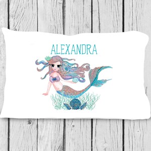 May include: White pillow with a mermaid illustration and the name "ALEXANDRA" printed in turquoise blue.