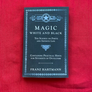 May include: A black book titled "Magic White and Black" by Franz Hartmann. The book cover features an ornate design with a star and the text "The Science on Finite and Infinite Life" and "Containing Practical Hints for Students of Occultism."