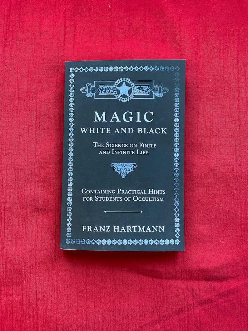 May include: A black book titled "Magic White and Black" by Franz Hartmann. The book cover features an ornate design with a star and the text "The Science on Finite and Infinite Life" and "Containing Practical Hints for Students of Occultism."
