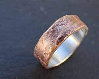 May include: A textured copper wedding band with a silver interior.