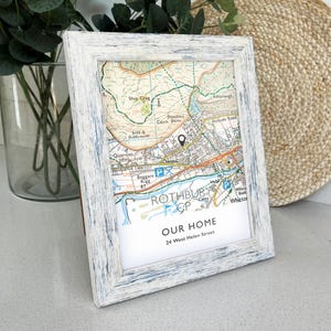May include: A framed map print with a white distressed wood frame. The map shows the town of Rothbury, with the text "OUR HOME" and the address "24 West Helen Street" at the bottom. A black pin marks a location on the map.