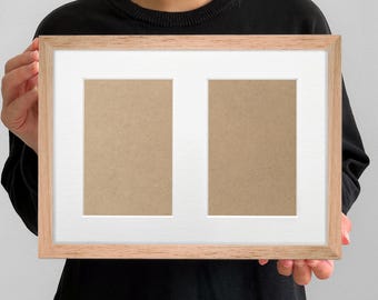 May include: A light brown wooden picture frame with a white mat and two openings. The frame is held by a person wearing a black sweater. The openings are filled with a light brown material.