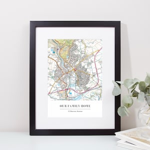 May include: Framed map print in a black frame with a white mount. The map shows a detailed, colourful representation of a town or city, with roads, buildings, and natural features. The text "OUR FAMILY HOME" and address "12 Shorton Avenue" are printed at the bottom.