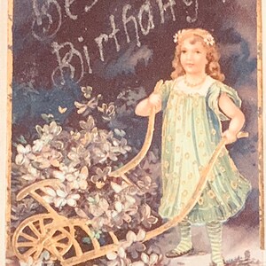 Antike 1900er Jahre geprägte, glitzernde Geburtstagspostkarte, beste Geburtstagswünsche, kleines Mädchen, das Blumenwagen schiebt, frühe geteilte Rückseite