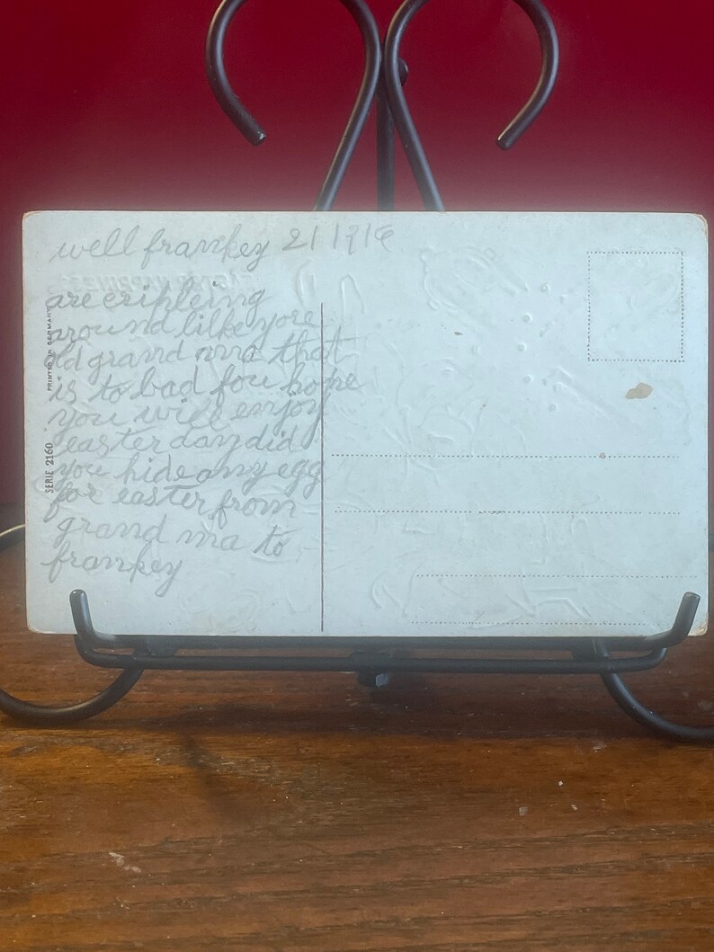 Op de afbeelding: Een vintage ansichtkaart met een handgeschreven bericht dat luidt: "well franckey 211119 are cripleing brou id lilke yore ad grand and that is to bad fou boke Leaster day did will enjor you hide any egg for easter from grand ma to frankey".