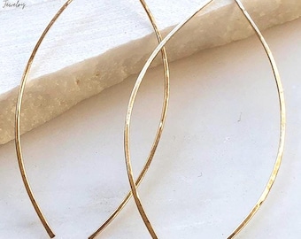 May include: A pair of gold-toned marquise-shaped earrings with a hammered texture. The earrings feature a slender, curved wire design that forms an elongated leaf shape. The text L.A. OSBORN Handcrafted Jewelry is visible in the upper left corner.
