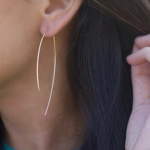Delicate handcrafted threader earrings in the shape of an arc L.A.Osborn model showing the dainty hoop arc earring which is slightly longer at 2.5" in on the backside and approximately 2" on the front side of the earring.