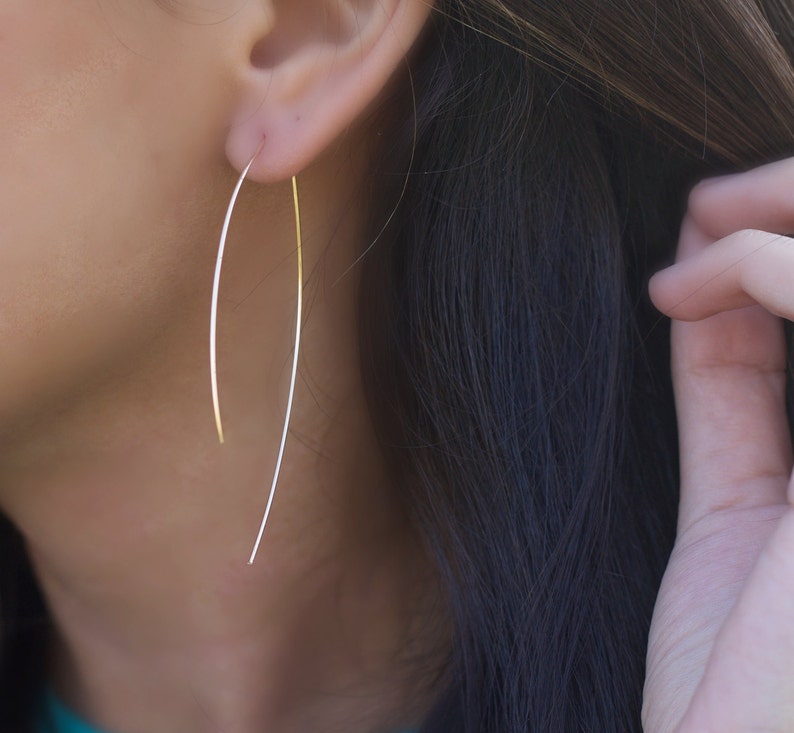 Delicate handcrafted threader earrings in the shape of an arc L.A.Osborn model showing the dainty hoop arc earring which is slightly longer at 2.5" in on the backside and approximately 2" on the front side of the earring.