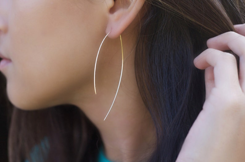 Delicate handcrafted threader earrings in the shape of an arc L.A.Osborn model showing the dainty hoop arc earring which is slightly longer at 2.5" in on the backside and approximately 2" on the front side of the earring.