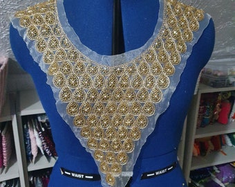 May include: A gold beaded trim with a sheer white fabric backing. The trim is shaped like a V and is designed to be sewn onto a garment.