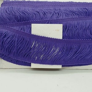 May include: Purple fringe trim with a textured woven base. The fringe is approximately 2.5 cm long.