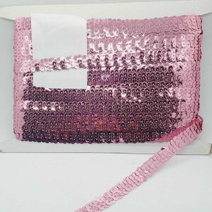 Puede incluir: Borde de lentejuelas rosa con un acabado brillante. El borde tiene aproximadamente 2,5 cm de ancho y es perfecto para agregar un toque de brillo a cualquier proyecto.