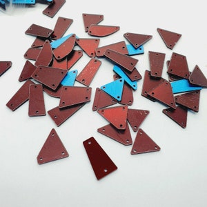 Puede incluir: Un gran surtido de lentejuelas triangulares y rectangulares de color marrón y azul. Las lentejuelas tienen una superficie brillante y reflectante.