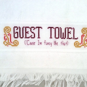 May include: White hand towel with embroidered text "GUEST TOWEL (Cause I'm fancy like that)" in burgundy and gold thread.
