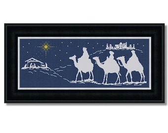 May include: A framed cross-stitch design depicting the three wise men riding camels towards a star in the night sky. The scene is set against a dark blue background with white silhouettes of the camels, men, and a star.
