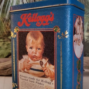 May include: Blue and gold Kellogg's Toasted Corn Flakes cereal box with a picture of a baby holding a spoon and bowl. The text on the box reads "Always ready for Kellogg's Toasted Corn Flakes".