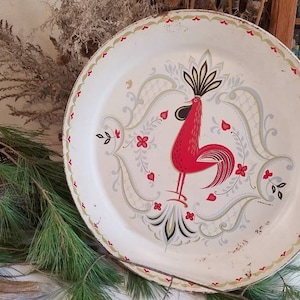 May include: A white metal serving tray with a red rooster design. The rooster is surrounded by green and black floral patterns. The tray has a red and green border.