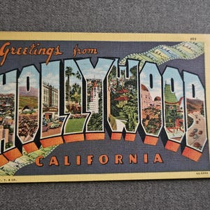 May include: Vintage postcard with the words "Greetings from HOLLYWOOD CALIFORNIA" in large, colorful letters. The letters are filled with images of Hollywood landmarks and scenery. The postcard has a yellow border and is set against a gray background.