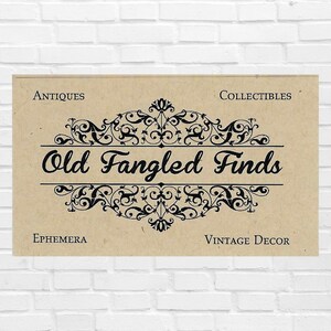 K&ouml;nnte beinhalten: Ein rechteckiges beiges Schild mit dem schwarzen Text Old Fangled Finds in Schreibschrift, zentriert zwischen kunstvollen schwarzen Schn&ouml;rkeln. Die W&ouml;rter Antiques und Collectibles stehen oben, Ephemera und Vintage Decor unten.