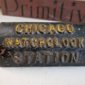 May include: A black cast iron sign with gold lettering that reads "CHICAGO WATCHCLOCK STATION".