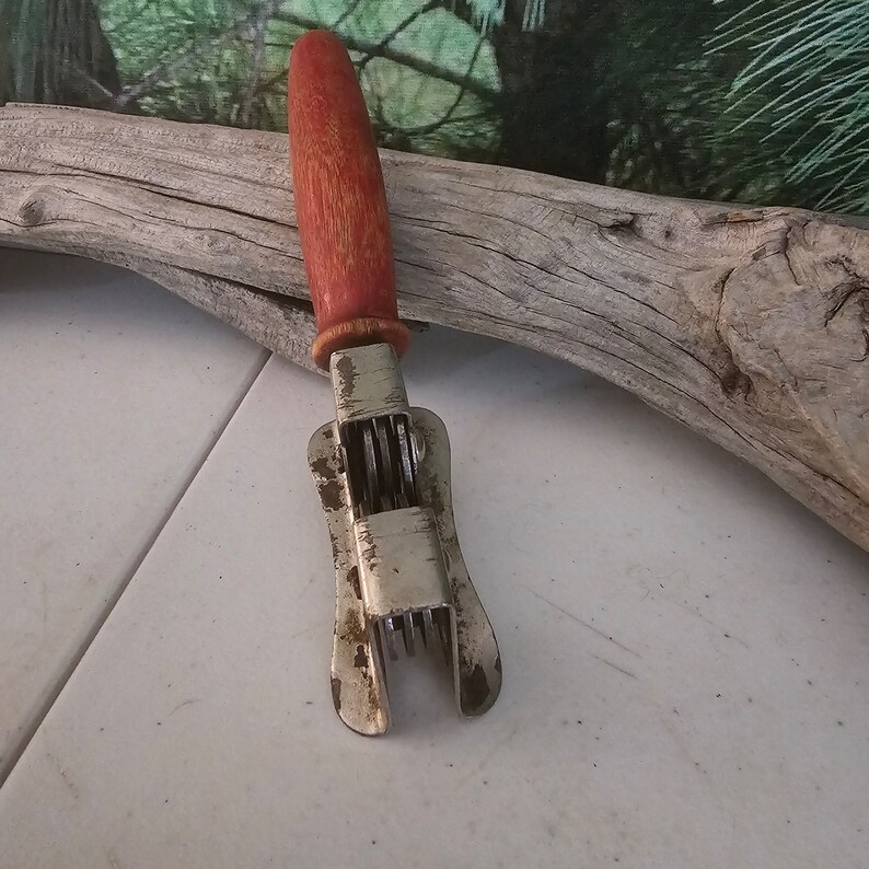 K&ouml;nnte beinhalten: Ein vintage K&uuml;chenwerkzeug mit rotem Holzgriff und mehreren Klingen zum Schneiden von Gem&uuml;se. Das Werkzeug ist aus Metall.