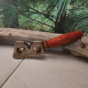 K&ouml;nnte beinhalten: Ein vintage Messersch&auml;rfer mit einem roten Holzgriff. Der Sch&auml;rfer hat zwei Metallr&auml;der und der Text "Good Luck" ist auf dem Metall aufgedruckt.