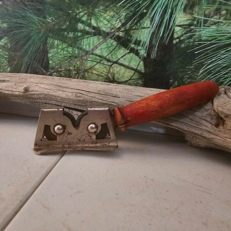 K&ouml;nnte beinhalten: Ein vintage Messersch&auml;rfer mit einem roten Holzgriff. Der Sch&auml;rfer hat zwei Metallr&auml;der und der Text "Good Luck" ist auf dem Metall aufgedruckt.