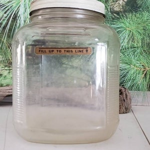 May include: A clear glass jar with a white lid and a label that reads "Fill up to this line".