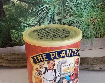 May include: A vintage Planters Peanuts tin with a red, white, and blue label. The label features a cartoon illustration of Mr. Peanut, a man in a top hat and monocle, pouring peanuts into a jar. The text on the label reads "The Planters" and "Fresh Roasted Peanuts".