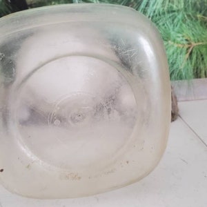 May include: A clear plastic milk jug with a textured surface. The jug is empty and has a circular indentation on the bottom.