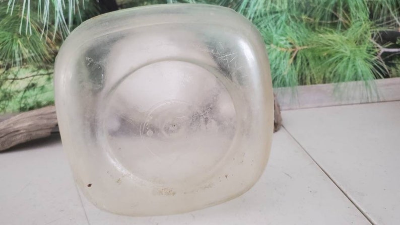 May include: A clear plastic milk jug with a textured surface. The jug is empty and has a circular indentation on the bottom.