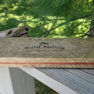 Puede incluir: Una caja marr&oacute;n con una franja roja y el texto "Regent Sheffield" en letras doradas. La caja est&aacute; etiquetada con "The Exceptional Razor in Cutlery" y "Guaranteed Forever Sharp".
