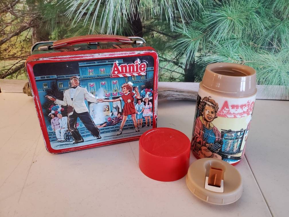 A vintage Annie lunchbox made by Aladdin which comes with a thermos and  does have wear. - Antique Mystique