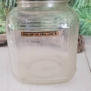 May include: A clear glass jar with a white lid and a label that reads "Fill up to this line".