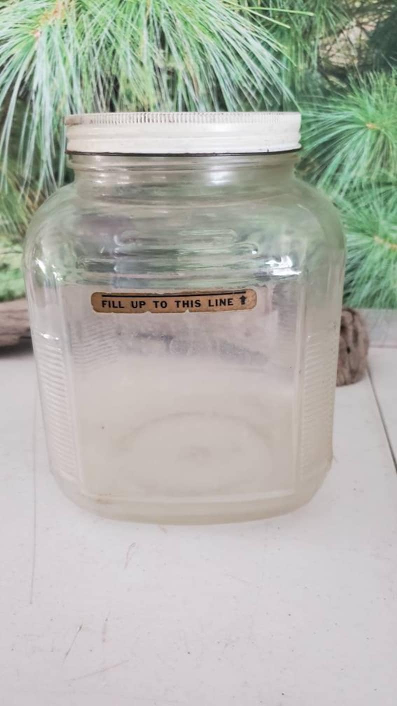 May include: A clear glass jar with a white lid and a label that reads "Fill up to this line".