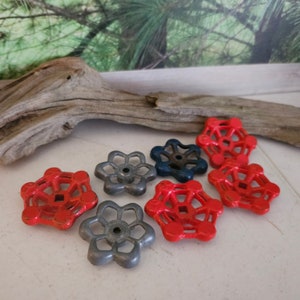 May include: A collection of seven vintage water valve handles. Four are red and three are gray. The handles are made of metal and have a starburst design.