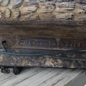 May include: A close-up of a brown duck decoy with a metal base. The base is labelled "Flambeau".